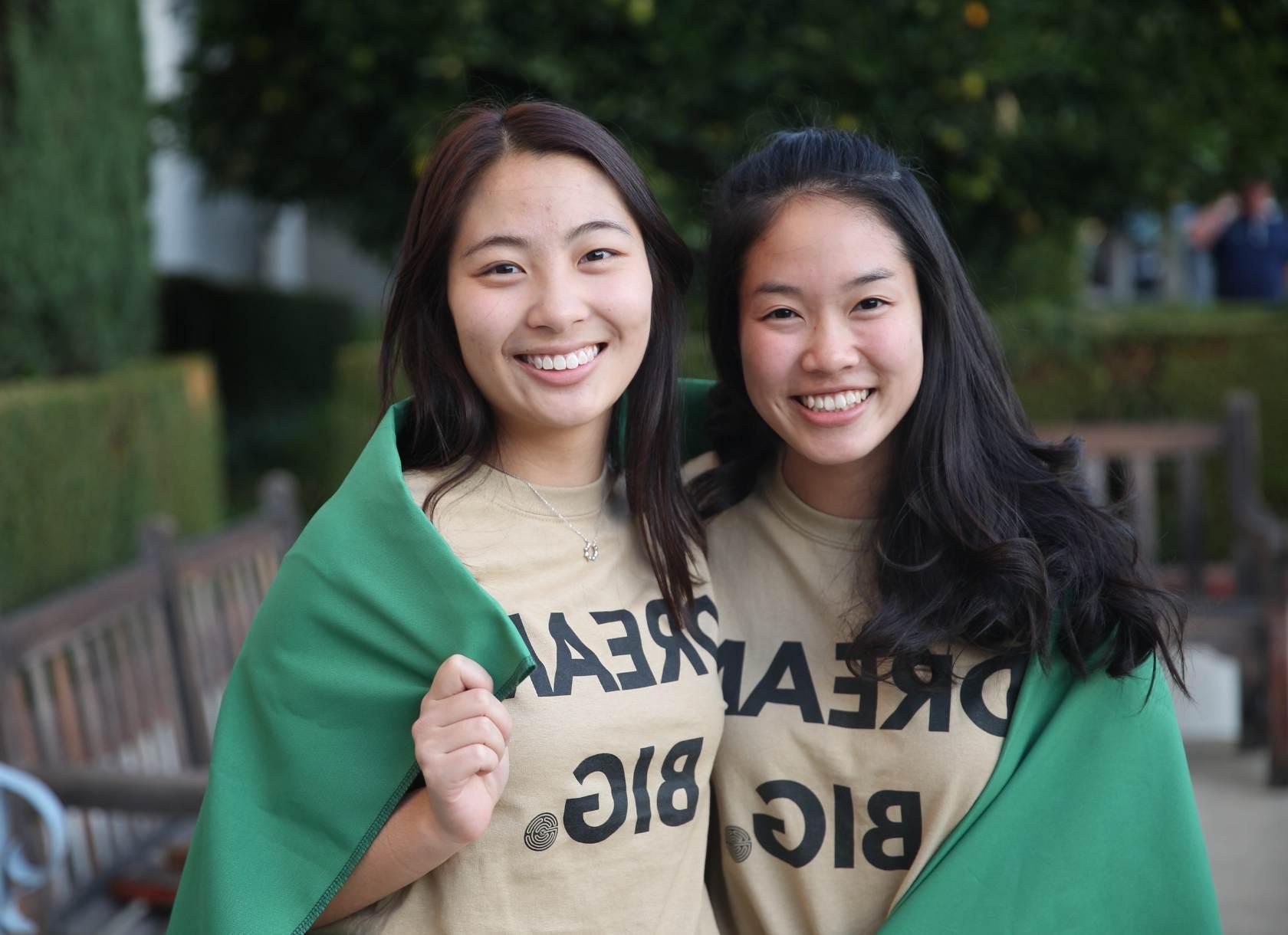Two students wearing shirts that say dream big with cape around them